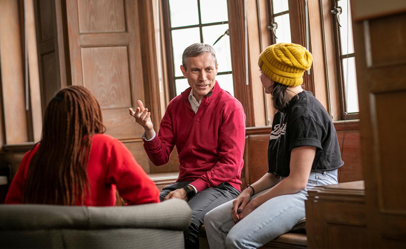 Dean Alex Colvin sits and talks with two students in the Diugherty Lounge