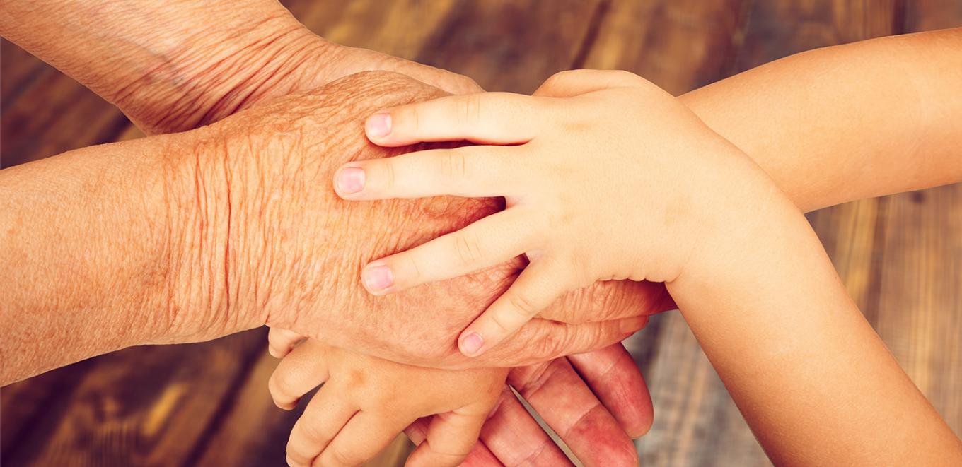 small, young hand on top of an older, wrinkled hand