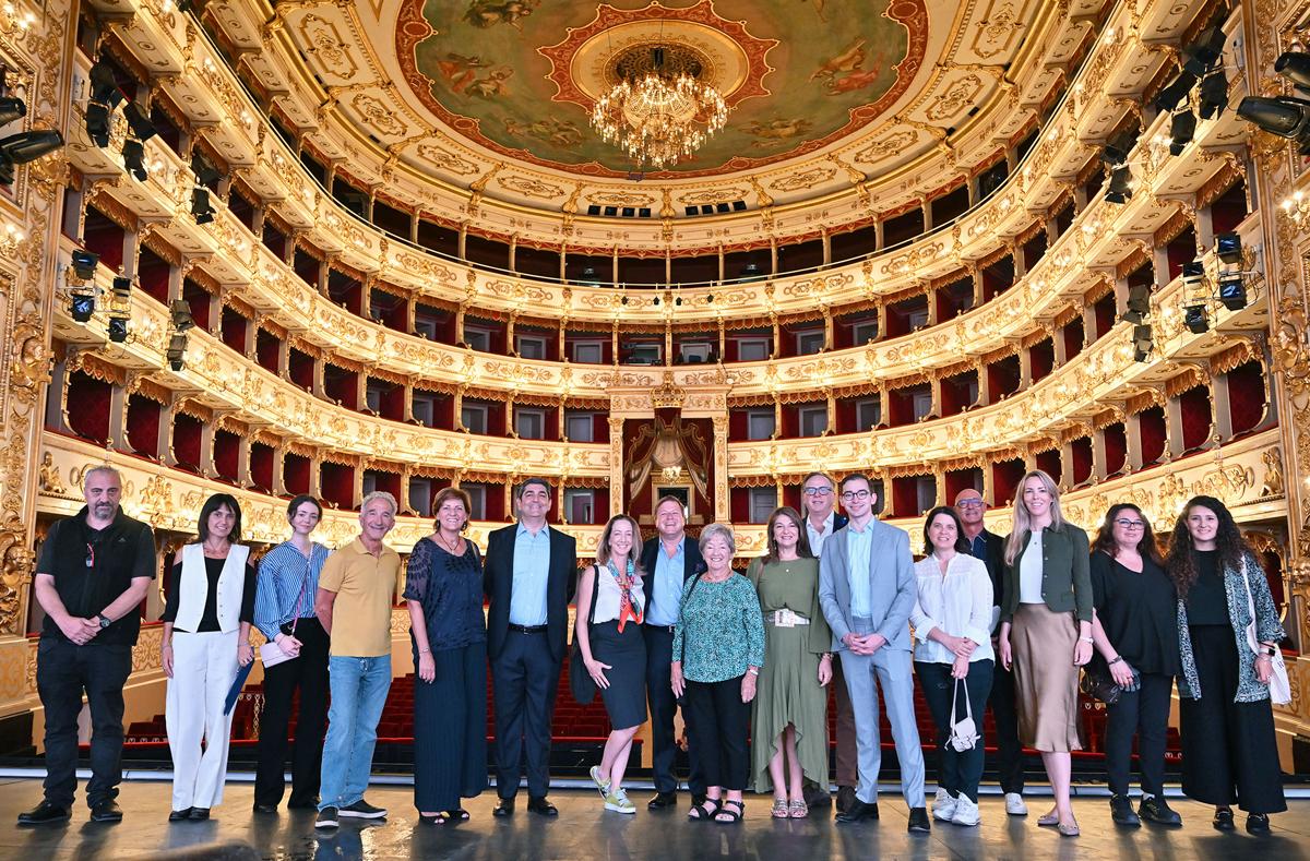 group of people standing on the stage with a beautiful theater behind them