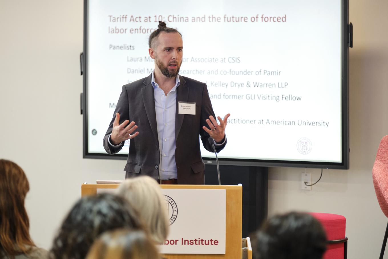 Daniel Murphy stands at a podium at the 2025 Global Labor Institute conference in New York City, with a screen behind him listing the title of his panel discussion
