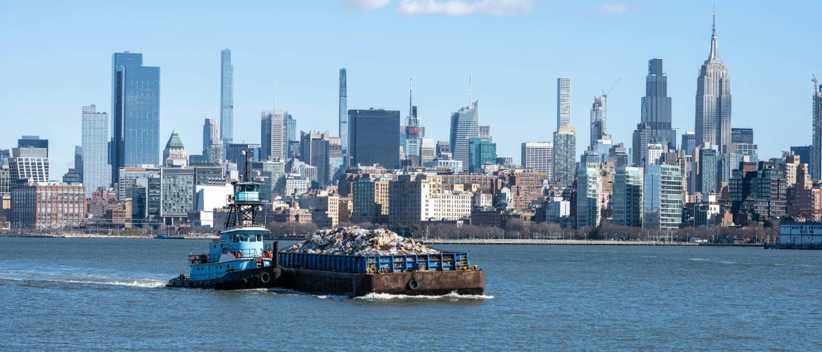 A boat in the river with the NYC skyline in the background