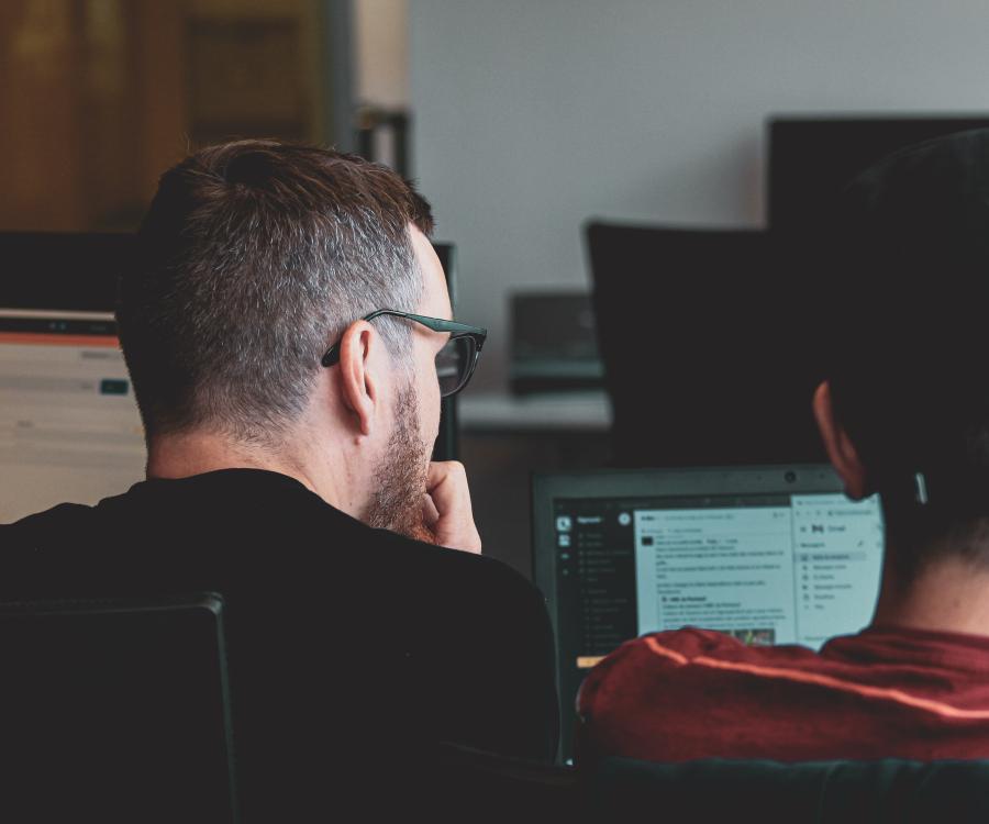 An older and younger person discussing data on a screen