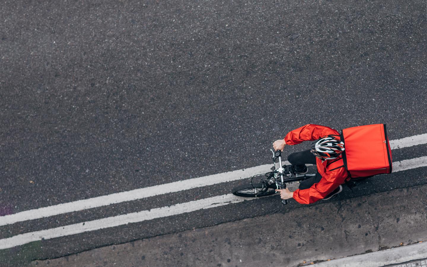 Delivery worker cycling along a paved road