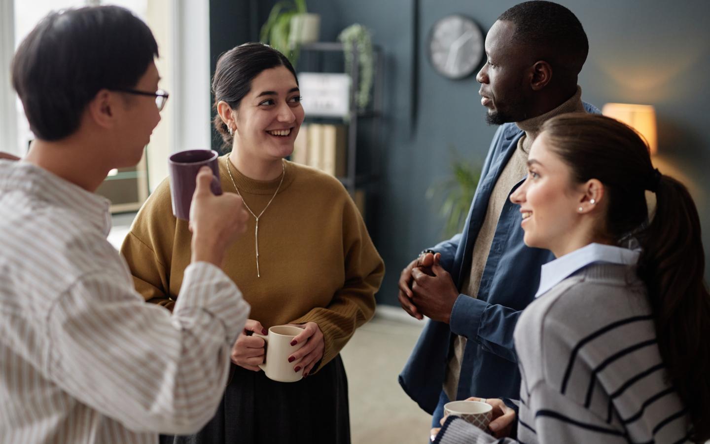 Group of four coworkers chatting during coffee break in an office