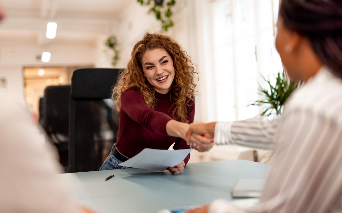 A professional setting showcasing a young woman engaging in a handshake with a colleague