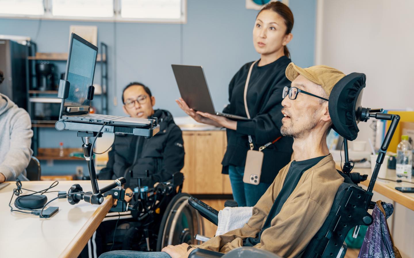 Man in a wheelchair sitting at a computer with coworker next to him
