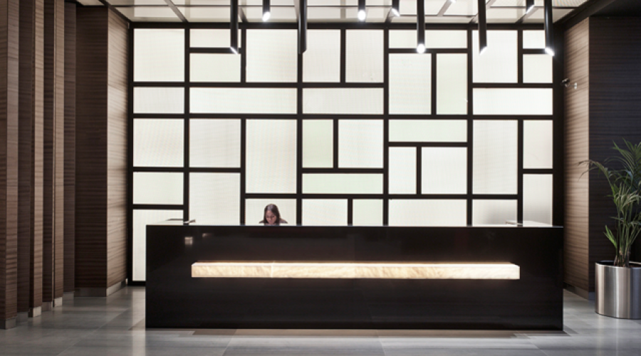 A woman sits behind a hotel reception desk