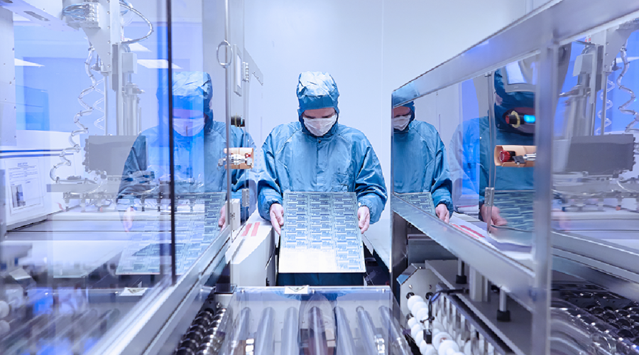 Scientific worker in full protective gear with tray of samples