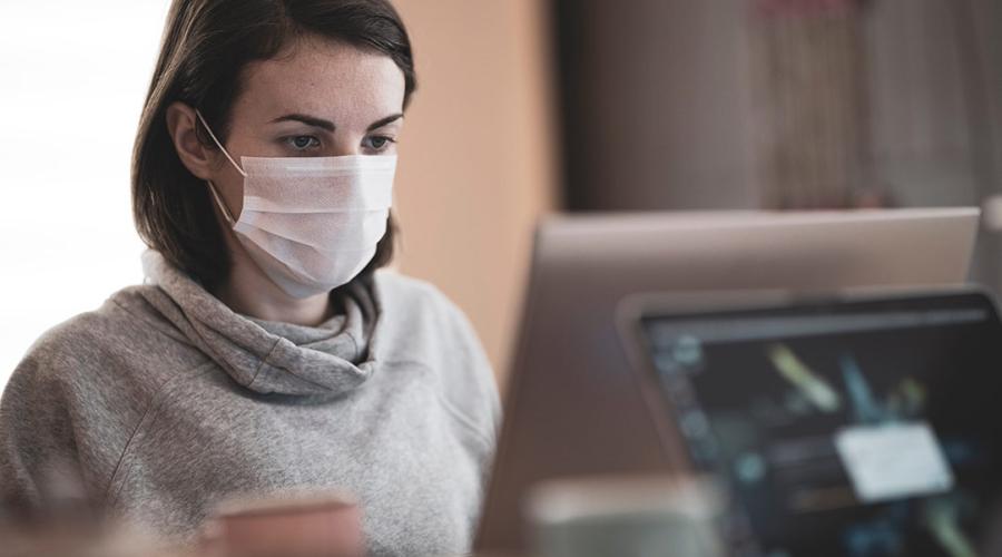 someone wearing a mask while working at a computer monitor