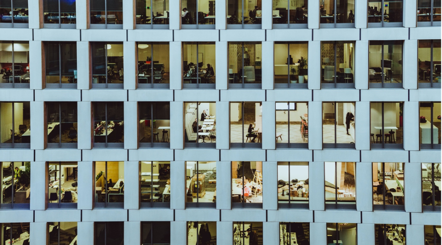 View of individuals living different lives through apartment building windows.