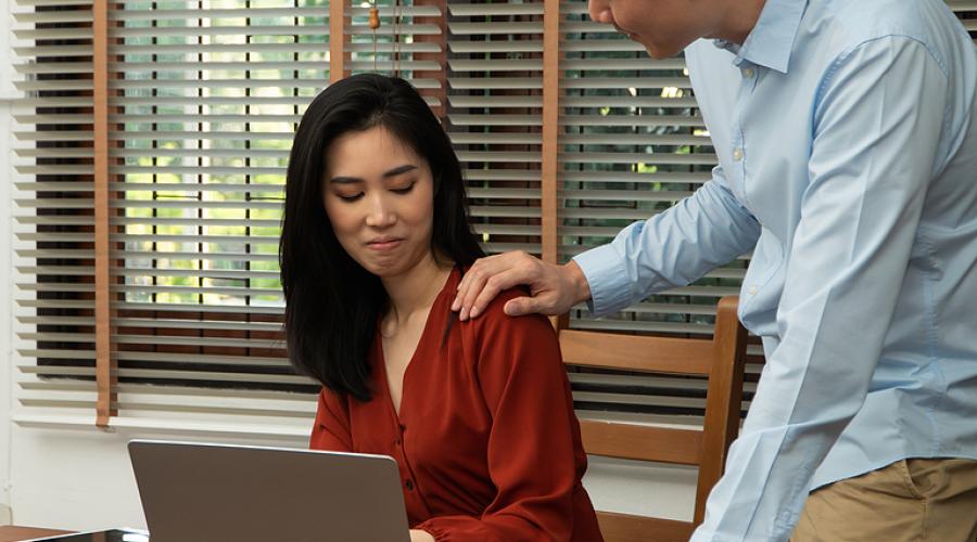 A woman cringes as her co-worker places a hand on her shoulder