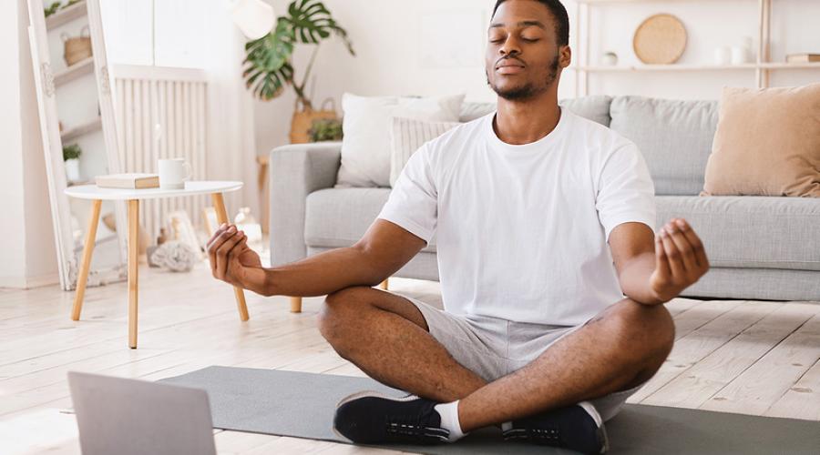 A young man practices yoga in his living room.