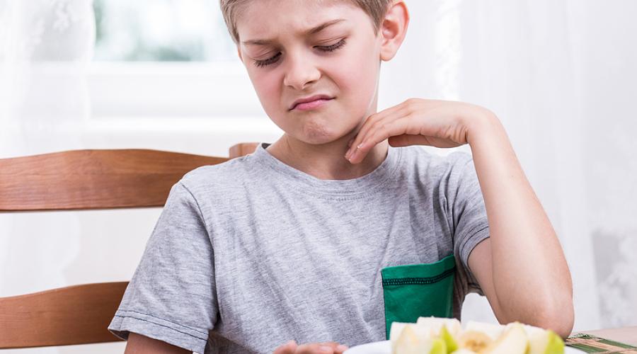 A young boy refusing to eat an apple