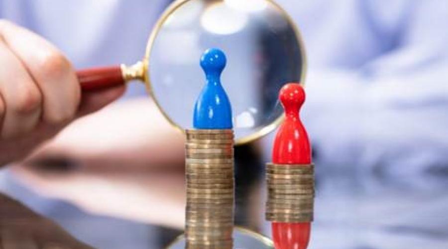 An allusive image of coins stacked with one stack higher than another with a token on top of each stack and a magnifying glass behind indicating examination