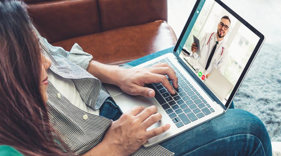 A couple speaking to a doctor online with a laptop computer.