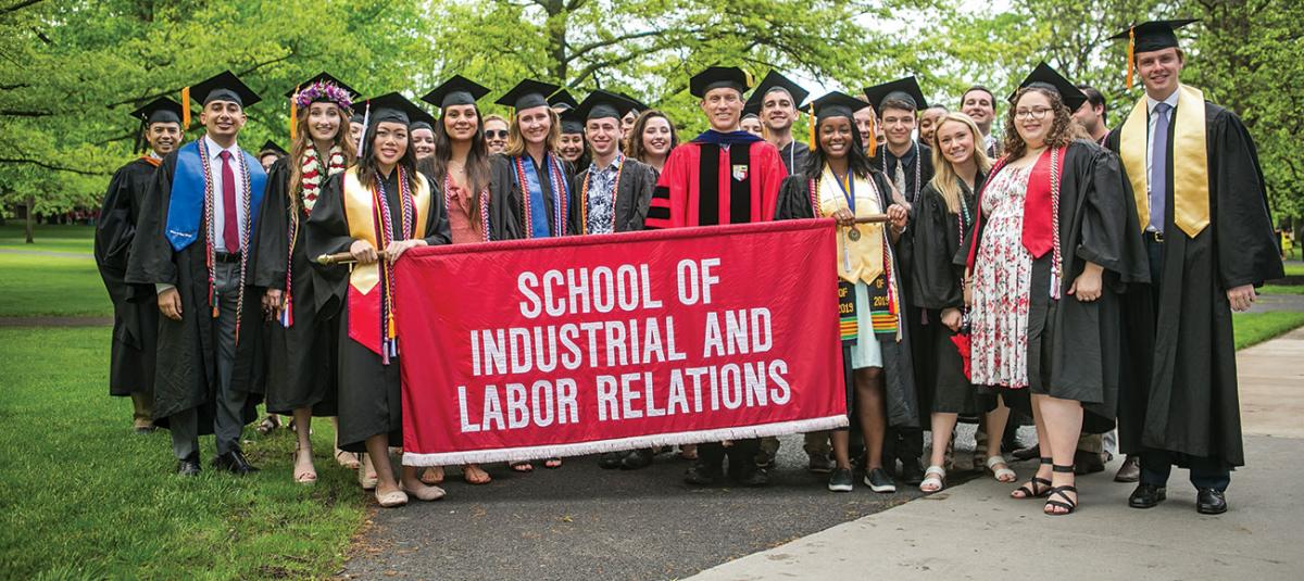 ILR graduates pose behind the school's banner that is carried during commencement 