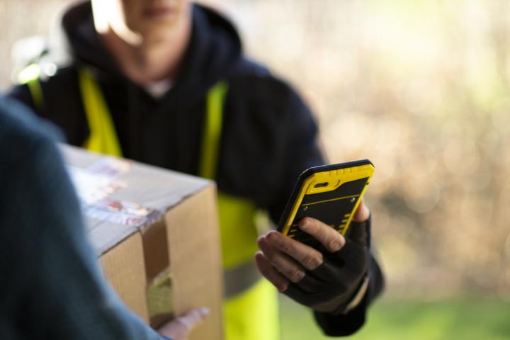 Delivery person using a cell phone to complete a delivery