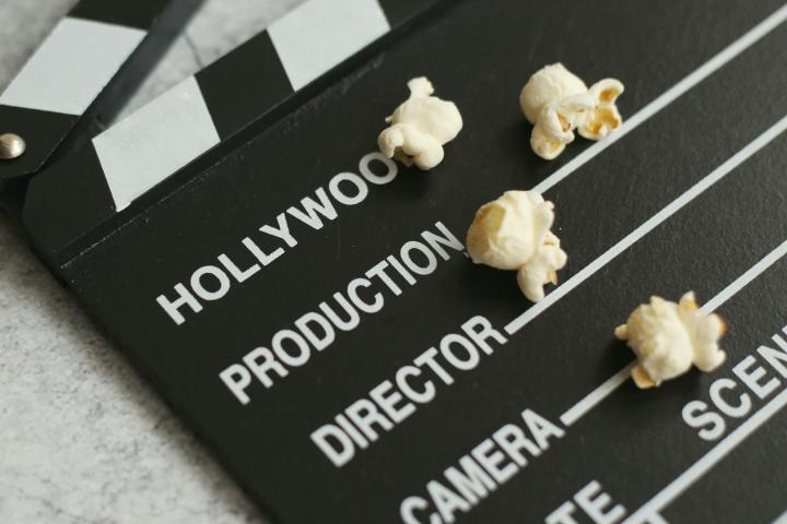 Movie clapperboard that says "Hollywood, Productino, Director, Camera, Date" with popcorn on it