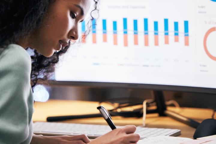 A person working at a desk with a screen with a bar chart
