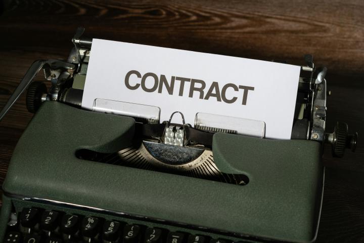 Photo of a piece of paper that says "CONTRACT" coming out of a typewriter