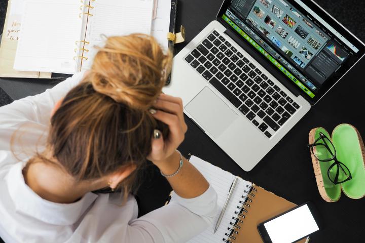 woman sitting in front of macbook with her head in her hands
