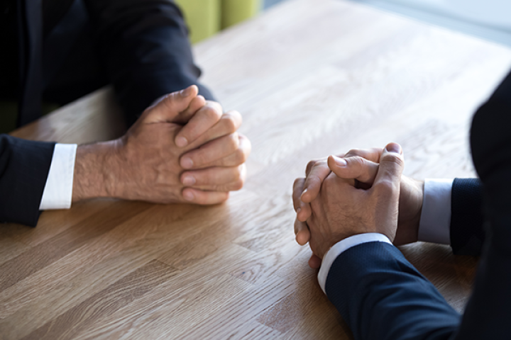 stand off at table - two people with hands clasped