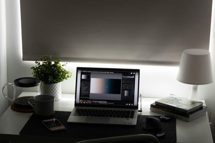 Photo of desk with laptop in front of window with shade drawn