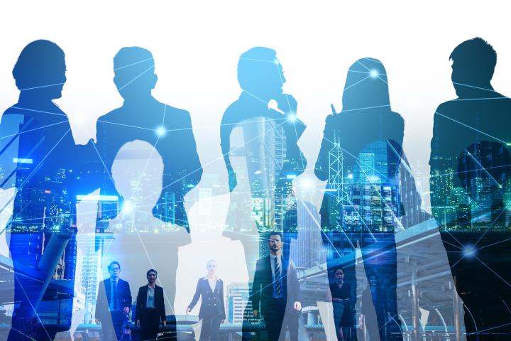 Silhouettes of business professionals standing and conversing, overlaid with a city skyline and digital network lines, representing collaboration, leadership, and a connected workforce.