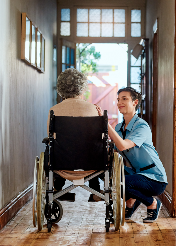 A nurse tends to a wheelchair bound patient in her home