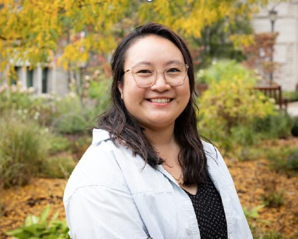 Fall foliage as background, dark haired, Asian woman, glasses, black shirt under jean button up